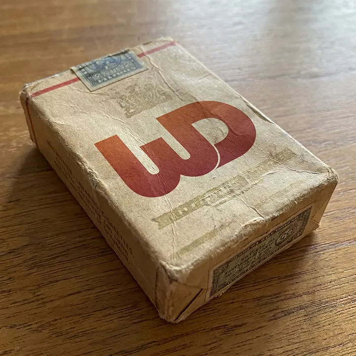 Vintage, weathered paper pack on a wooden surface featuring a prominent red WD logo.